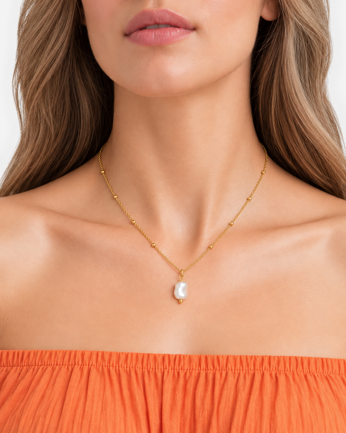 Alara gold-tone pendant necklace worn above an orange strapless neckline