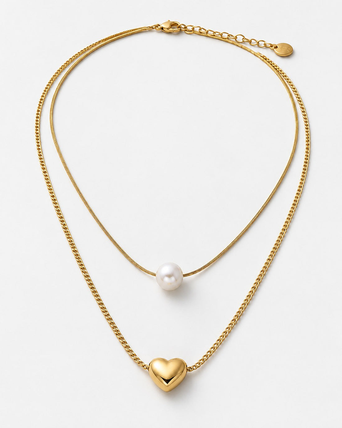 Layered gold-tone necklace with a smooth round white accent and separate heart pendant