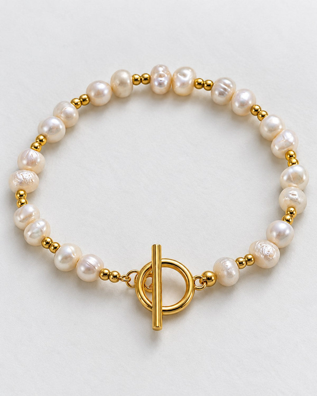 Bracelet with irregular white beads, paired gold-tone beads and a toggle clasp