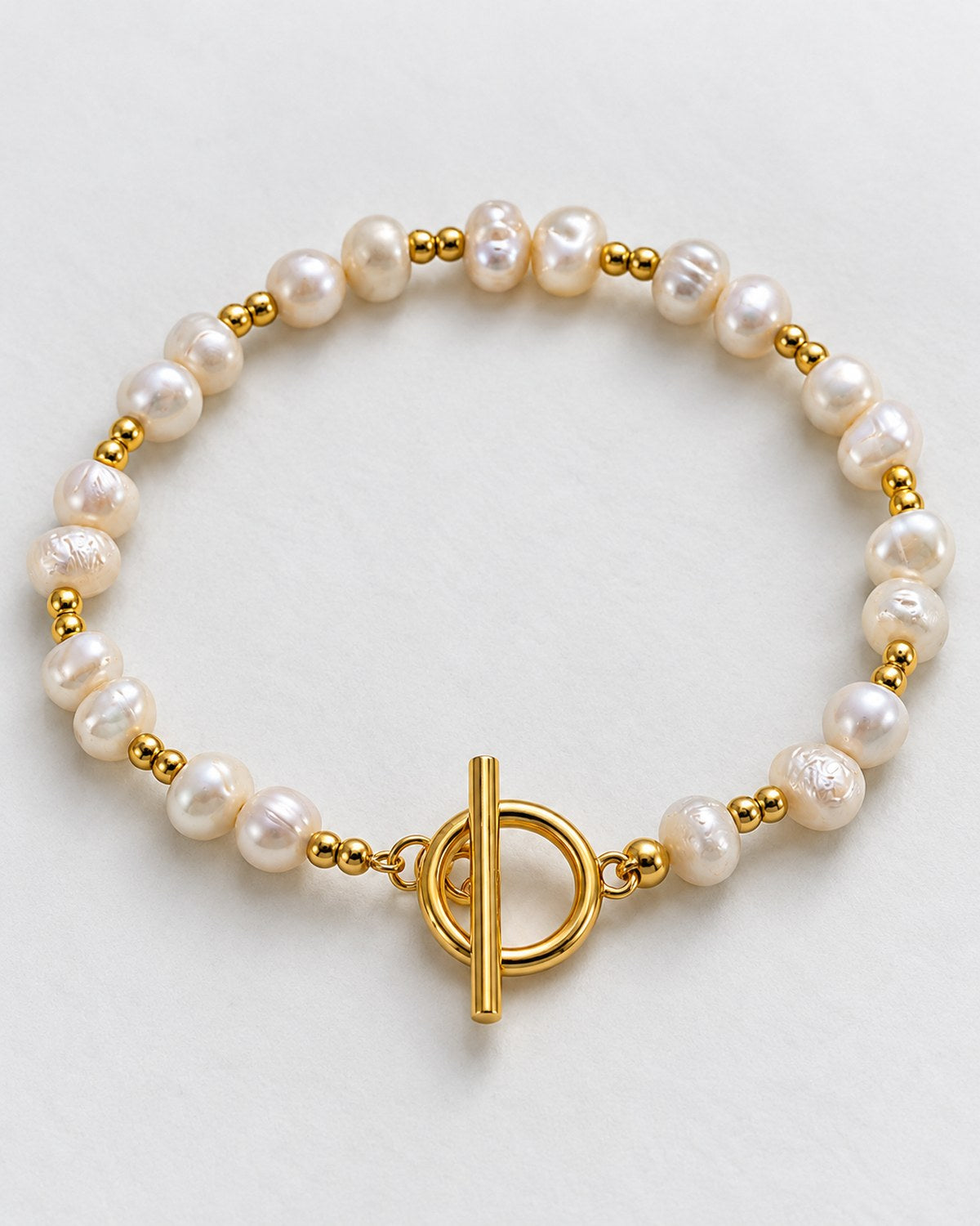 Bracelet with irregular white beads, paired gold-tone beads and a toggle clasp