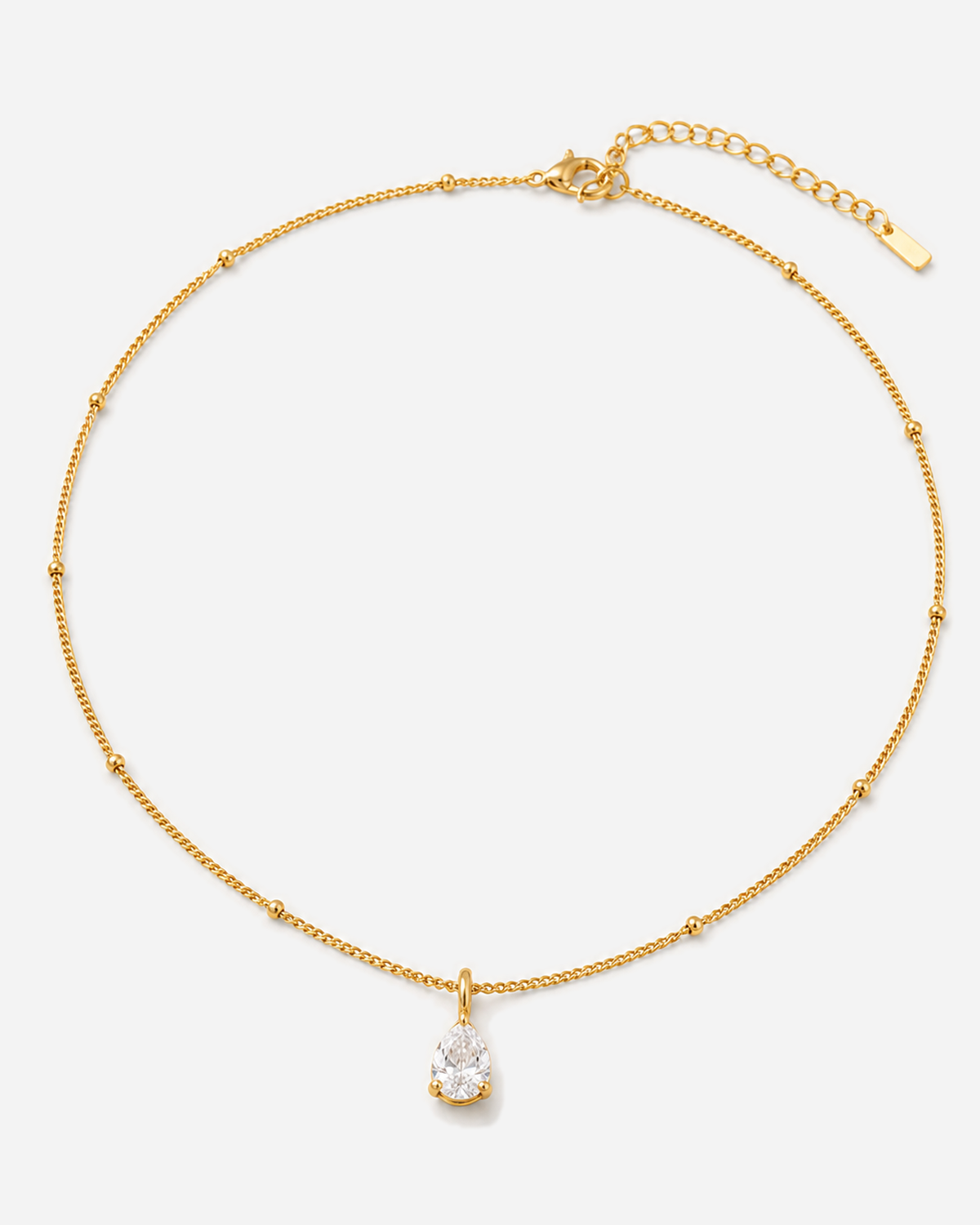 Gold-tone bead-station necklace with a clear teardrop pendant, clasp and extender