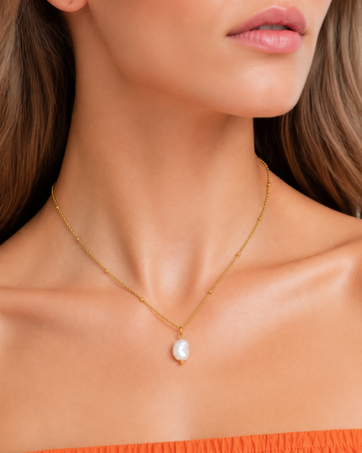 Alara Pearl Necklace — 05 — Gold three-quarter wearing view with papaya dress