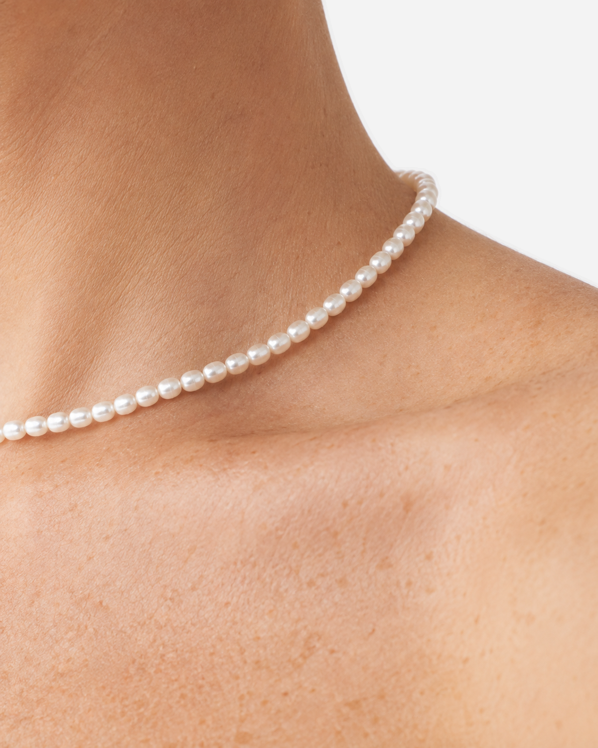 Extreme close-up of the Elara white oval beads worn at the neckline