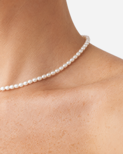 Extreme close-up of the Elara white oval beads worn at the neckline